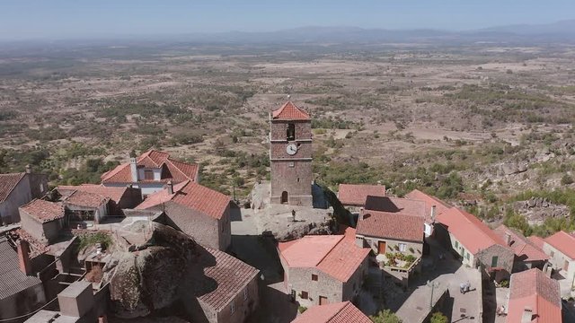 Aerial view of the clock tower Torre de Lucano in the ancient traditional village of Monsanto in Portugal. The drone rises and opens a panorama of the valley, unveiling shot