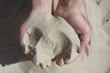 Female hands hold white sand with both hands. Sand flows through hands. Summer beach vacation