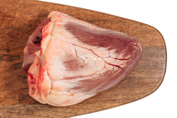 raw beef heart on a wooden board isolated on a white background. top view