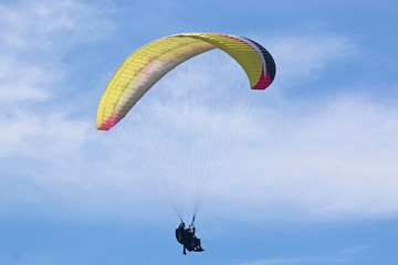 Tandem Paraglider flying wing in a blue sky	