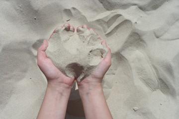 Female hands hold white sand with both hands. Sand flows through hands. Summer beach vacation