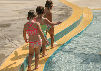 little girls walking along poolside playing follow the leader