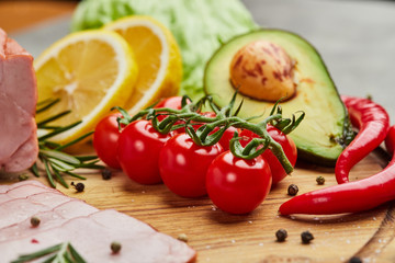 Fresh ripe tomatoes on a cutting board with avocado, peper and lemon