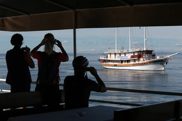 Silhouettes of tourists photographing a tourist ship