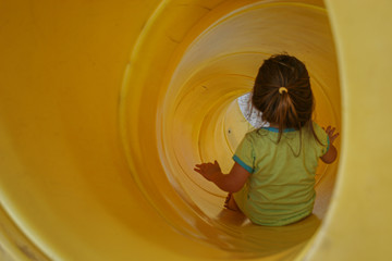 Little girl playing at playground during recess on swing and slide