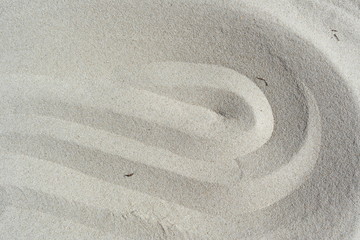 Fototapeta na wymiar Light beige sea sand beach textured background with wavy lines top view.