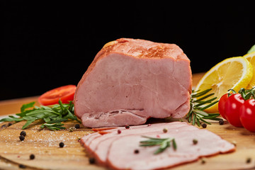 Sliced ham with spices, lettuce, avocado and tomatoes on wooden cutting board. Сold meat plate. Fresh prosciutto