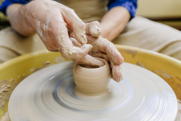hands make a vase behind a potter's wheel. ceramics. pottery, macro shooting