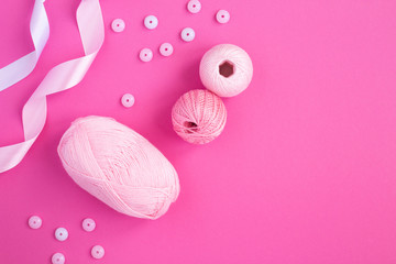 Pink knitting and decorative buttons on the pink background. Top view.  Copy space.