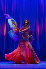 Dancer with long hair in orange neon  oriental costumes dance belly dance on the concert stage