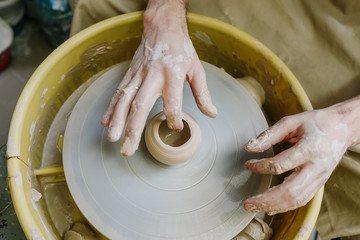hands make a vase behind a potter's wheel. ceramics. pottery, macro shooting