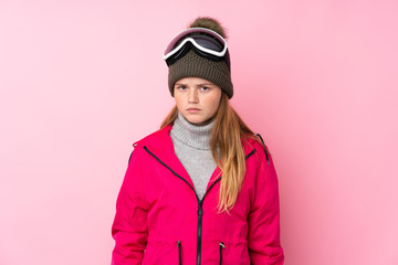 Ukrainian teenager skier girl with snowboarding glasses over isolated pink background sad