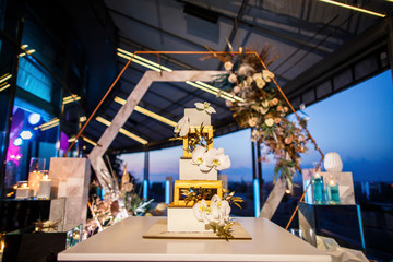 night wedding ceremony, the arch is decorated with flowers, candles and garlands of light bulbs and there is a wedding cake on the table
