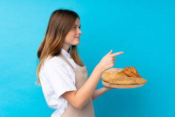 Ukrainian teenager chef uniform. Female baker holding a table with several breads pointing to the...