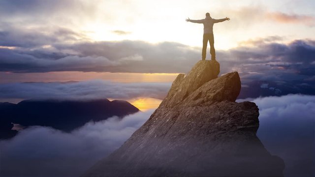 Cinemagraph Continuous Loop Animation. Adventurous Man Hiker With Hands Up on top of a Steep Rocky Cliff. Sunset or Sunrise. Landscape Taken from British Columbia, Canada. Concept: Adventure, Explore