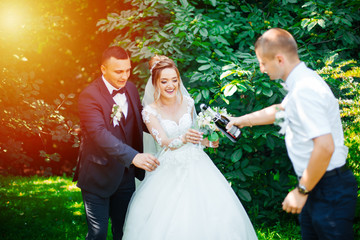 Cheers! Newlyweds with friends drink champagne of the outdoors. People celebrate and raise glasses of wine for toast.