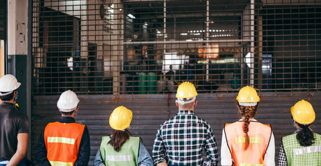 Back view group of industrial or engineer corporate workers wear hard hat helmet standing line up...