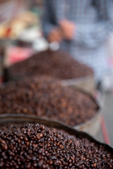 Heap of coffee bean with blurred background of coffee barrels, macro