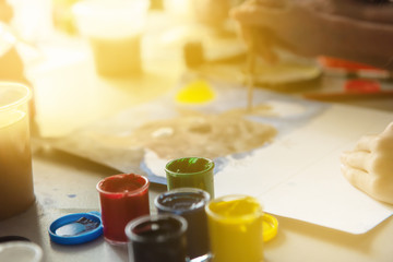 concept drawing. The child draws in gouache. On the table are jars of paint. Blurred hand of a child