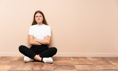 Fototapeta na wymiar Ukrainian teenager girl sitting on the floor with confuse face expression