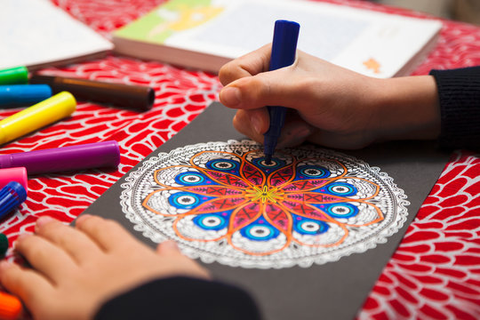Close-up of girl's hands coloring a mandala