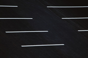 Empty parking during quarantine. White markings for cars on black asphalt.