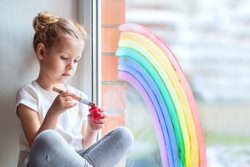 A little girl with blond hair holds paint cans in her hands. 