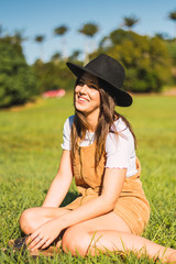 Portrait of wonderful white female model with hat while walking through the field with background of tree