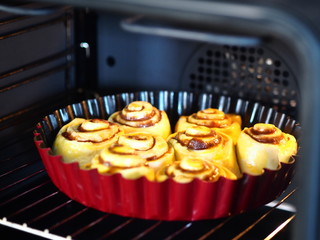 Homemade cakes, rolls with chocolate filling, in a red form for baking in a home kitchen oven.