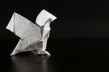 Close-up view of white paper origami eagle on the black background. Hobbies theme.
