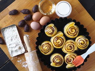 Pastry background.Raw rolls with chocolate filling, in a baking dish with ingredients on a cutting Board.