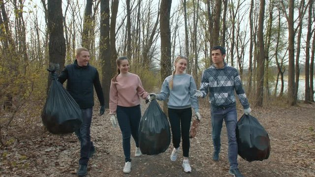Friends with trash bags walk in the park