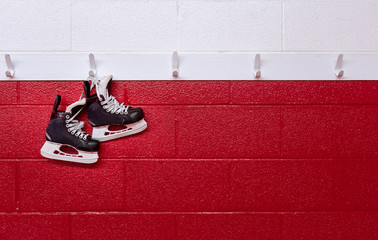 Hockey skates hanging over red wall in locker room with copy space 