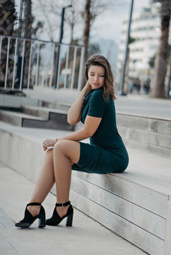 A beautiful young brunette girl is walking in the city posing for the camera. Sunny weather and promenade in Antalya