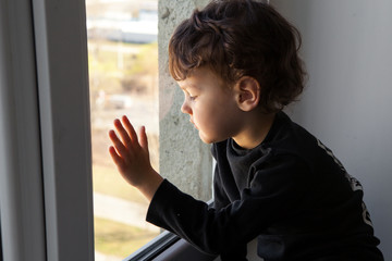 the child misses walks on the street and fresh air sitting on the windowsill by the window.