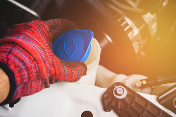 Hand of mechanic man with red glove is opening water wiper lid tank of a car,Automotive part concept.