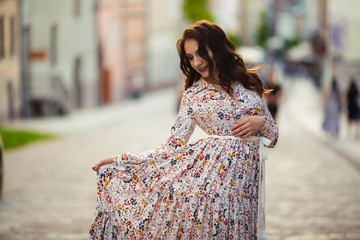 brunette walks through the streets of Lviv in a beautiful long dress