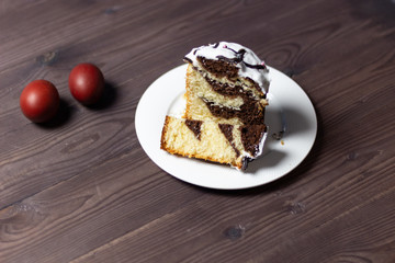 easter chocolate cake pieces in plate on wooden brown table, colored eggs