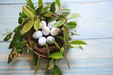 Fototapeta na wymiar Nest with small eggs. The nest is decorated with green branches. Easter theme. Spring. Scandinavian Easter.