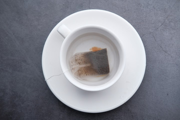 close up of tea bag and tea cup on table.