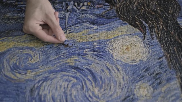 Finishing a puzzle. Hands putting down two puzzle pieces 
