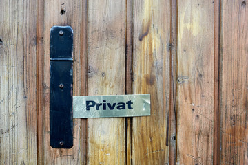 Lettering Privat on a rectangular brass plate on a wooden door with black fittings from the front