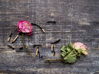 dead matches and a faded rose on the wooden table