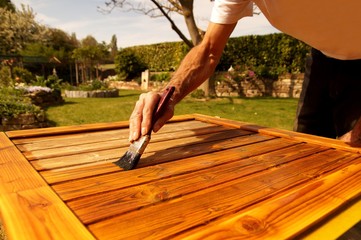 how do I use the paint brush correctly concept. Back to Front. woodwork outside. Male hand painting a door with a brush. Concept of renovation works, Carpentry details with woodwork and handyman.