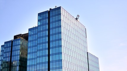 Obraz premium Blue curtain wall made of toned glass and steel constructions under blue sky. A fragment of a building.