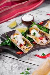 Tacos on corn tortilla with chicken and vegetables topped with sour cream. Mexican cuisine meal