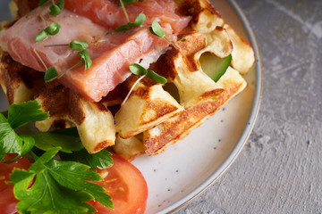 Tasty Homemade waffles with salmon, cucumber and herbs on plate