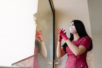Portrait of beautiful nurse or doctor in mask with syringe in hand standing near the window in abandoned medical clinic or asylum