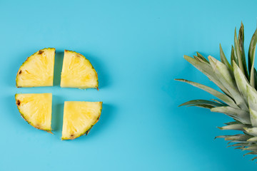 Fototapeta na wymiar Fresh pineapple slices on blue background with green leaves