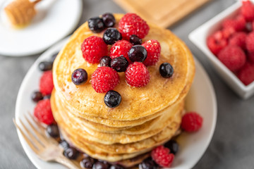 Sweet homemade pancakes with fruits on white plate.